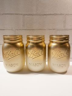 three gold mason jars sitting next to each other