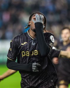 a man with dreadlocks is holding his hand up to his face as he walks off the field