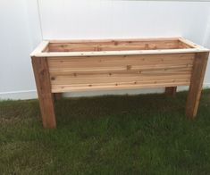 two wooden planters sitting in the grass near a white wall and green grass on the ground