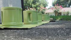 green coffee mugs are lined up on the ground