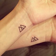 two small tattoos on the wrist that look like triangle and rhomdoid shapes