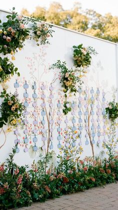 a large white wall with flowers and plants painted on it's sides in front of a brick sidewalk