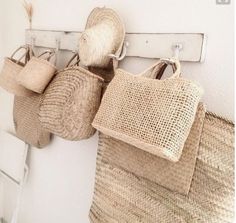 three straw bags hanging from hooks on the wall