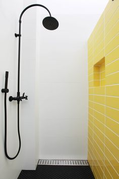 the shower head is next to the yellow tiled wall