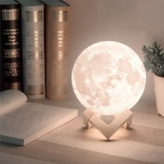 the moon lamp is sitting on top of a table next to books