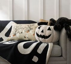 a black and white pumpkin pillow sitting on top of a couch next to a stuffed animal