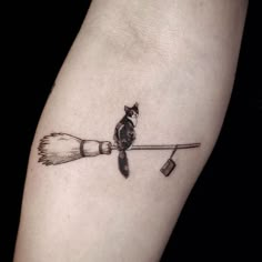 a cat sitting on top of a broom tattoo