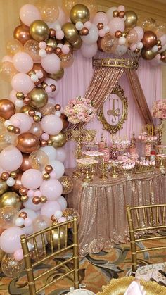 a table topped with lots of pink and gold balloons