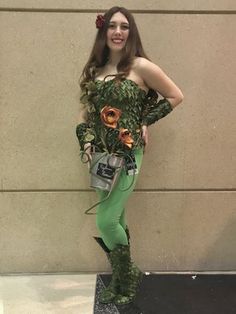 a woman dressed in green is standing next to a wall with flowers on her body