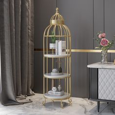 a gold birdcage stands next to a marble table