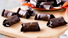 chocolate candy rolled up on a wooden cutting board next to a plate with oranges