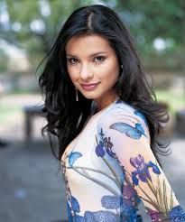 a woman with long black hair wearing a blue and white dress posing for the camera