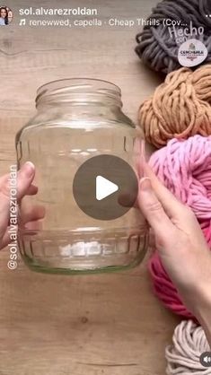 someone is holding a jar with yarn in it on a wooden table next to a crochet ball