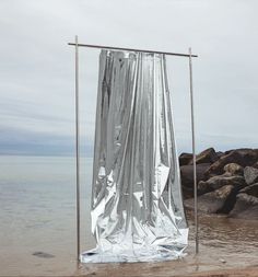 a piece of cloth is hanging from the side of a pole in the water near some rocks