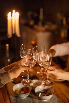 three people toasting with wine glasses on a table in front of two lit candles