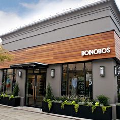 the front of a restaurant with plants and potted plants on the side of the building