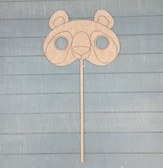 a paper cut out of a bear head on top of a wooden stick in the shape of a mask