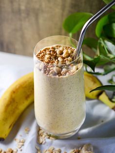 a glass filled with oatmeal next to a banana on a white cloth