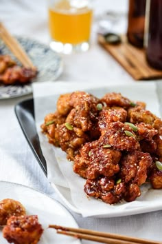 some food is sitting on a white plate with chopsticks and sauce in the background