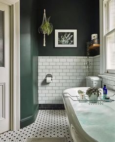 a bathroom with black and white tiles, green walls and a bathtub in the corner