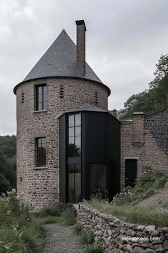 a house made out of rocks and stone with a tower on the top that is surrounded by grass