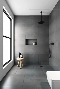 a modern bathroom with white walls and grey flooring, along with a large window