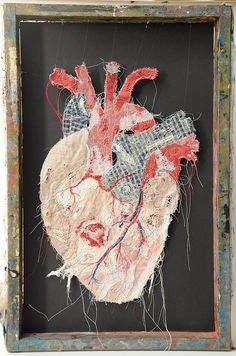 an altered photograph of a human heart in a wooden frame on a white wall with peeling paint