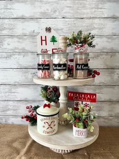 a table topped with jars filled with candles and christmas decorations on top of a cake stand