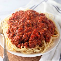 a plate of spaghetti with meat sauce on it and a fork next to the plate