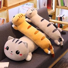 three stuffed animals laying on top of each other in a room with bookshelves