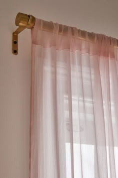 the curtain is hanging in front of the window with pink drapes on it's side