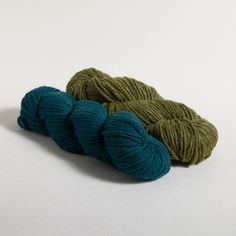 two skeins of yarn sitting next to each other on a white table top