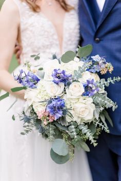 a bride and groom pose for a wedding photo in front of the camera with their bouquet