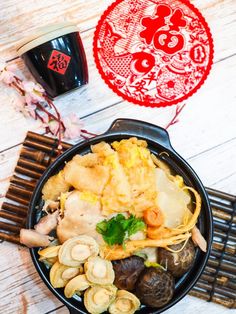 a pan filled with different types of food on top of a wooden table next to a cup