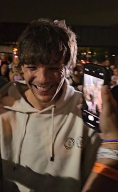 a man smiling and holding up his cell phone