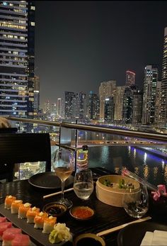 a table topped with sushi and chopsticks next to a river