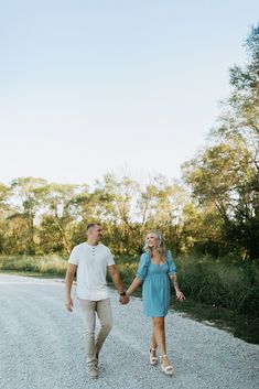 an engaged couple walking down the road holding hands