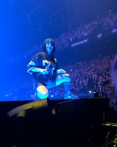 a man sitting on top of a piano in front of a crowd at a concert