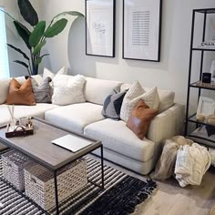 a living room with white couches and pillows on top of the couch, next to a coffee table