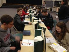 students are sitting at desks with books on them