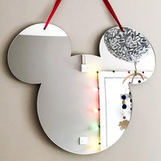 a mickey mouse mirror hanging on the wall with christmas lights around it's edges