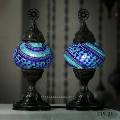 two blue and green glass vases sitting next to each other on top of a table