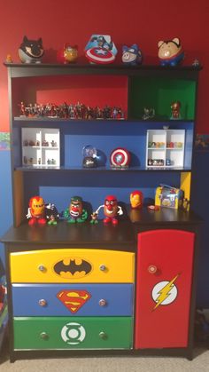 a child's dresser with various toys on top and bottom shelves in the shape of superheros