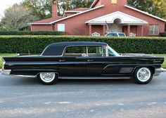 an old black car parked in front of a house