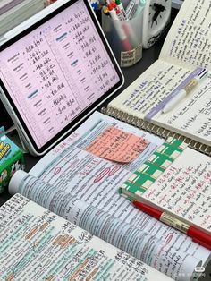 an open notebook sitting on top of a desk next to a computer monitor and pen