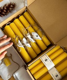 a box filled with yellow candles next to pine cones and twine string tied around them