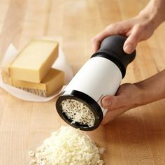 a person is grating cheese with a small grinder on a wooden table next to butter cubes