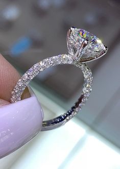 a close up of a person holding a diamond ring