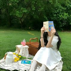 a woman sitting in the grass reading a book