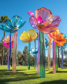 colorful glass sculptures in the shape of flowers on grass with palm trees in the background